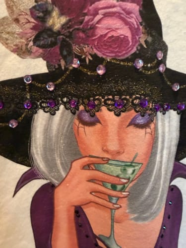 Reviewer's close-up of the witch shirt design, showing sparkly purple gems and glitter paint additions.