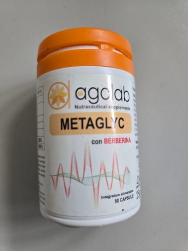Customer's white and orange bottle of Metaglyc glycemic control supplement on a flat surface.