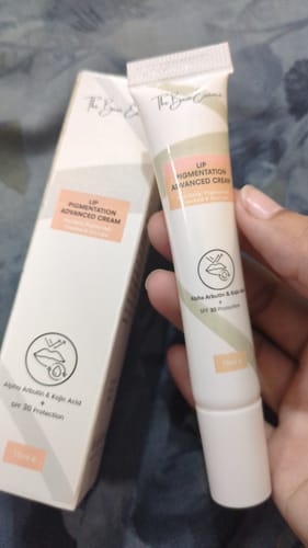 Customer's hand holding the Advance Lip Pigmentation Cream tube next to its matching product box.
