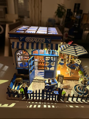 Customer's completed Santorini Café miniature kit, glowing with warm LED light in a dim room.