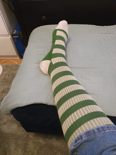Kundens gröna och vita randiga Diasocks stödstrumpor på benet för en bekväm passform