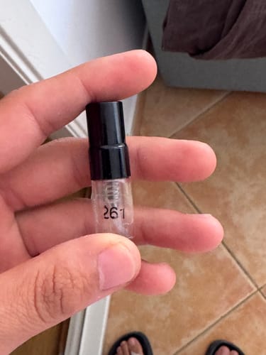 Reviewer's hand holding a small, clear sample bottle of the Tester Set, labeled with the number 261.