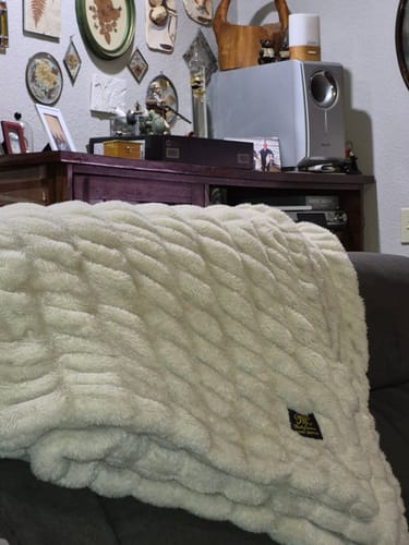 Customer's cream-colored Hugs Creme Brulee Blanket draped over a chair in a living room.