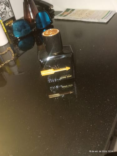 Customer's Adonis Goat perfume bottle with gold arrow detail, sitting on a black table with sunglasses nearby.