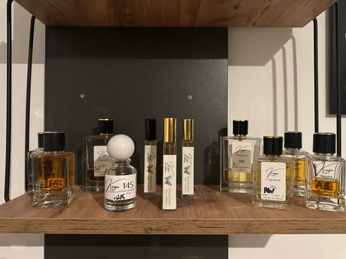 Kunden-Sammlung von Kiage Parfümflaschen in verschiedenen Größen, ordentlich auf einem Holzregal präsentiert.