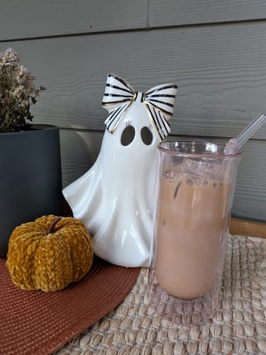 Customer's FLUR Iced Coffee Glass filled with coffee, set on a table next to a decorative ghost and small pumpkin.