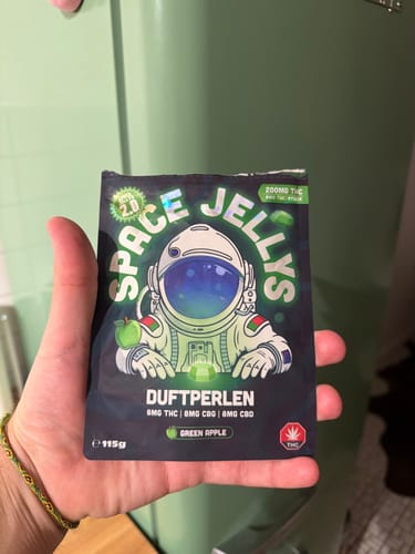 Kundenhand hält eine THC Spacejellies 2.0 Packung mit Astronauten-Grafik und dem Label Green Apple.