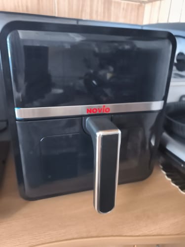 Customer's Novio StonePro air fryer, a sleek black appliance with a silver handle sitting on a wooden counter.