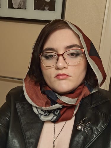 Reviewer wearing the blood red Murder Mystery All-Season Scarf over their head like a hood with a black leather jacket.