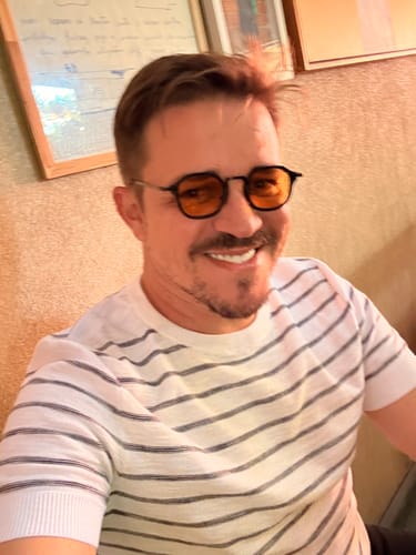 Customer's Óculos de Sol Bali com lentes alaranjadas sendo usado por uma pessoa em ambiente interno.