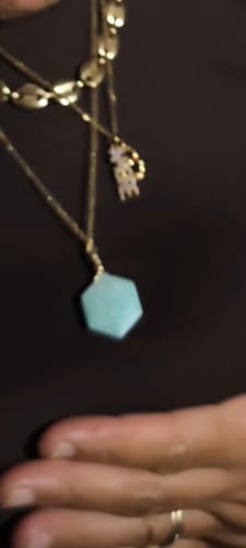 Customer's Collier amazonite sacré with a hexagonal pendant, worn around the neck against a dark background.