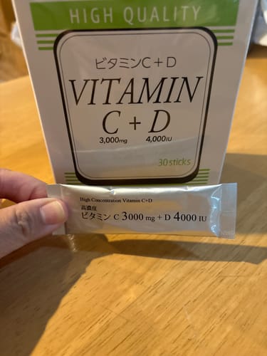 Reviewer's hand holding a silver stick of Wakasapri for Pro Vitamin C+D in front of the product box.