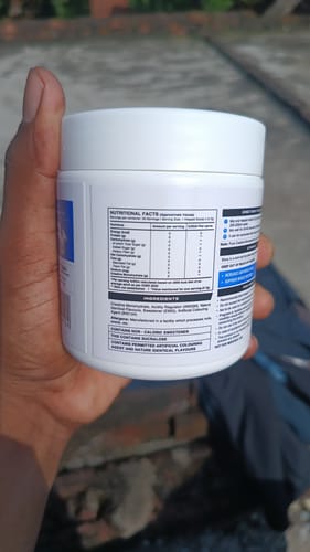 Customer's hand holding a white Wellcore Creatine Monohydrate container, showing the nutritional information label.