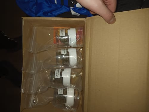 Customer's box containing four small plastic jars of Granddaddy Purple THC-A flower.