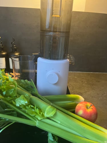 Customer's frischer Stangensellerie Bio Sparpreis-Box neben einem Entsafter und einem Apfel auf der Arbeitsfläche