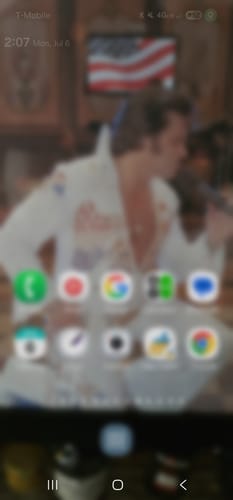 Customer's view of a blurred mobile phone screen displaying an Elvis Presley wallpaper