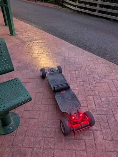 Customer's Shredlights SL-300+ headlight and SL-R1+ brake light on a skateboard, glowing on a brick path at night.