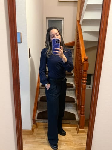 Customer's reflection in a mirror wearing navy Pantalón Líneas Lurex trousers, paired with a long-sleeve top.
