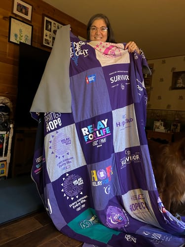 Customer's Project Repat T-Shirt Quilt held up, featuring various purple Relay for Life event t-shirts.