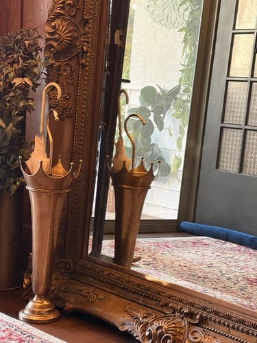 Customer's Theo Victor gold metal umbrella stand reflected in a large ornate hallway mirror.
