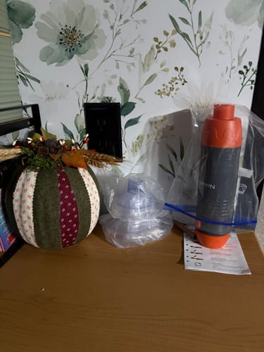 Customer's Lifetime Warranty choking device and clear masks, kept on a wooden counter with a decorative pumpkin.