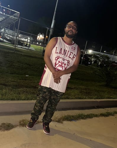 Customer's white and maroon basketball jersey with 'LANIER' and a bulldog logo, worn outdoors at night.