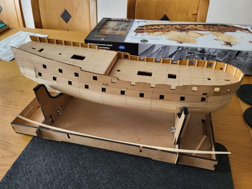 Customer's Royal Fortune model ship on a wooden stand, showing the light wood hull construction.
