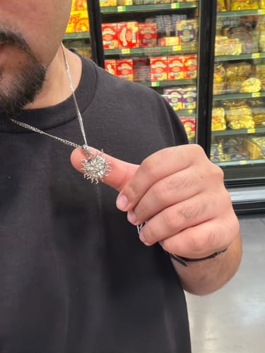 Customer's Stainless Steel Curb Chain being held up by a hand to show a silver sun-shaped pendant.