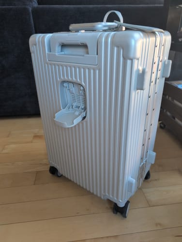 Reviewer's silver Labour Day Bundle 6.0 suitcase showing a damaged cup holder component on the exterior.