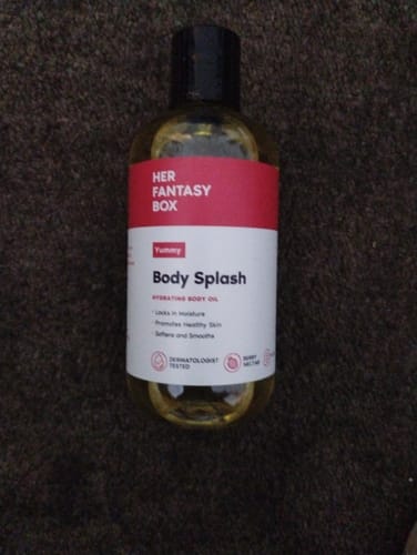 Customer's Yummy Body Splash Oil bottle from the Fruity Skin Body Oil Bundle, standing on a dark carpeted floor.