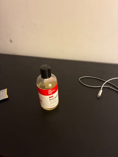 Customer's Yummy Body Splash oil bottle sitting on a dark table surface.