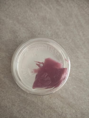 Customer's THC-A 55% Hash Pink Melt showing a pink-purple, smeared texture inside a glass container.