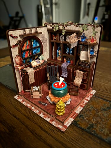 Customer's completed The Potion Workshop miniature kit featuring a tiny cauldron, stained-glass window, and potion bottles.