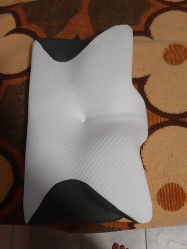 Customer's ergonomic memory foam pillow, white with grey panels, shown from above on a patterned surface.
