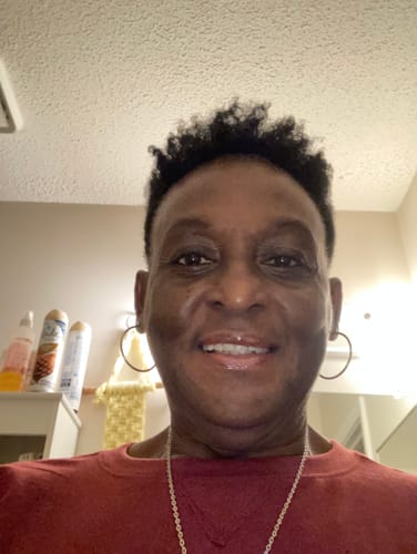 Reviewer smiling, with bottles of Body Glaze Scent from Heaven on the counter behind them.