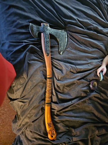 Customer's Leviathan axe with detailed dark metal blade and wooden handle, resting on a dark fabric surface.