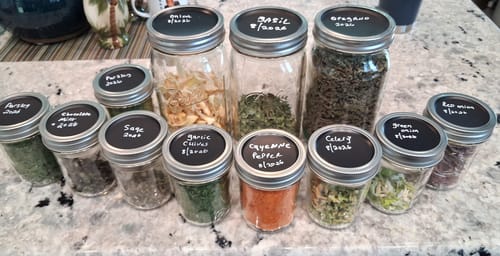 Customer's Chalkboard Top Mason Jar Lids used on many labeled, herb-filled glass jars on a countertop.