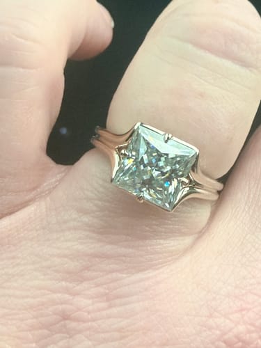 Customer's grey princess cut moissanite ring on a hand, highlighting the subtle grey-blue tone.