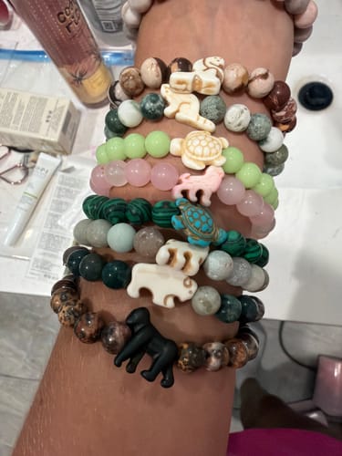 Customer's arm wearing a stack of multiple Mystery Bracelet animal-themed beaded bracelets.