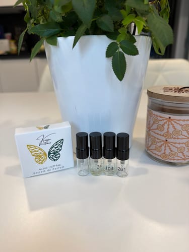 Customer's Tester Set featuring a white box and four small glass perfume samples standing on a table.