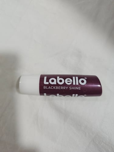 Customer's Labello Blackberry Shine lip balm tube on a white fabric background.