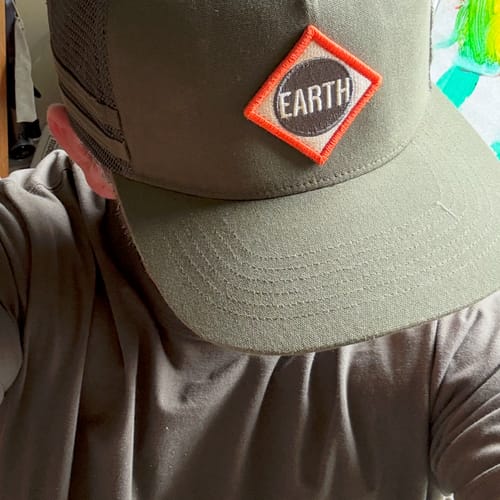 Customer's Big Flat Bill Structured Mesh Hat featuring a green earthy patch with the word EARTH in a diamond shape.