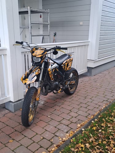 Customer's PIRATERAGE graphics kit installed on a black and yellow motocross bike parked outdoors on a patio.