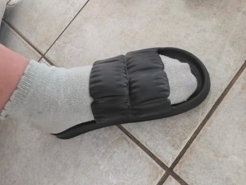 Customer's black Nouvelles sandales nuages worn over a light grey sock on a tiled floor.