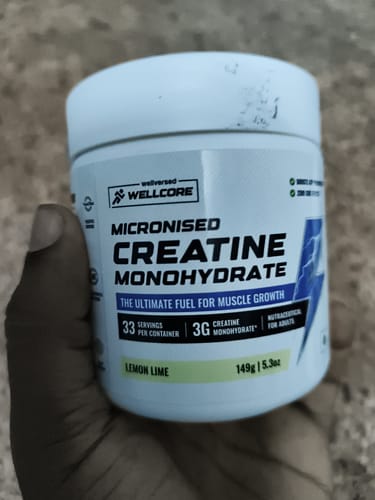 Reviewer's hand holding a jar of Wellcore Pure Micronised Creatine Monohydrate in Lemon Lime flavor.