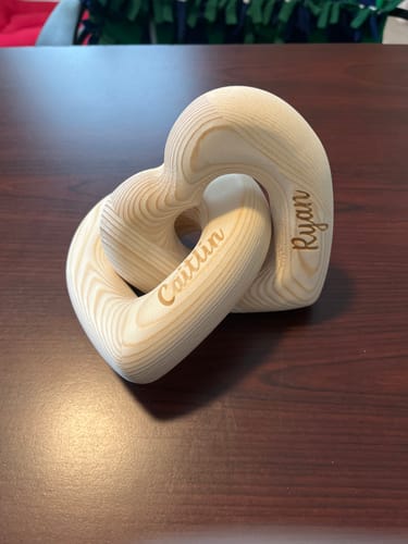 Customer's Personalized Infinity Heart Sculpture made of light wood with the names Caitlin and Ryan engraved on it.