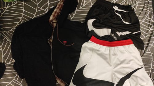Customer's Aelfric Eden zip-up hoodie shown in black and plaid, resting on a patterned bedspread.