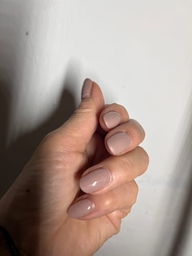 Customer's hand showing short, rounded nails finished in a smooth, chic nude Caramel Cream gel polish.