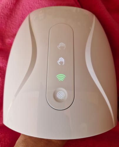 Customer's HandCare+ Regeneráló Kézmasszírozó in light beige with illuminated control panel icons and green light.