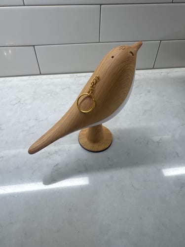 Customer's Glow Bird wooden sculpture featuring a metal chain and a small hole on its back.